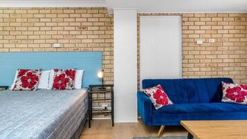 A room with a bed, a blue sofa, and a small table.