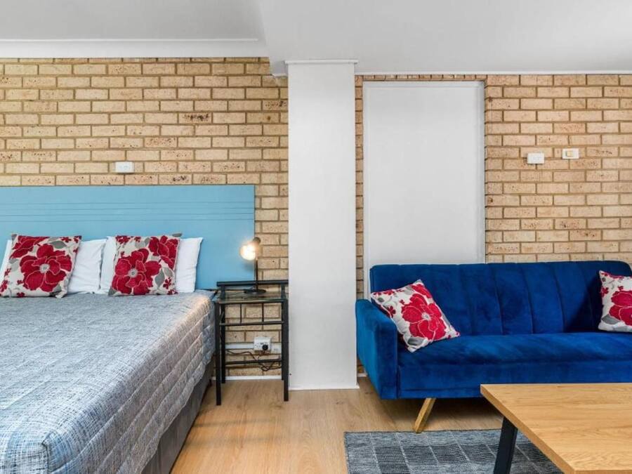 A room with a bed, a blue sofa, and a small table.