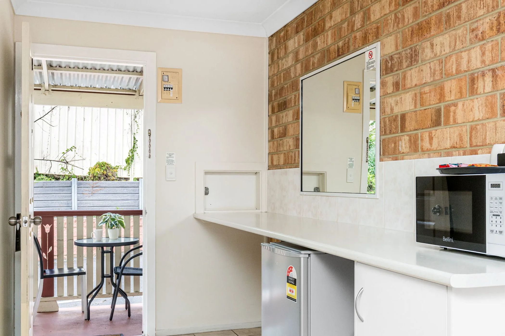 Una cocina compacta con microondas, refrigerador y un pequeño comedor con mesa y sillas.