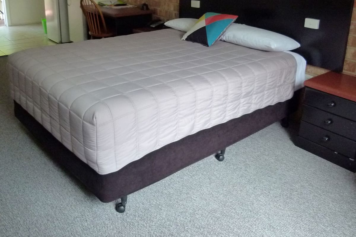 Una habitación de hotel con cama, escritorio, silla y una pequeña kitchenette.