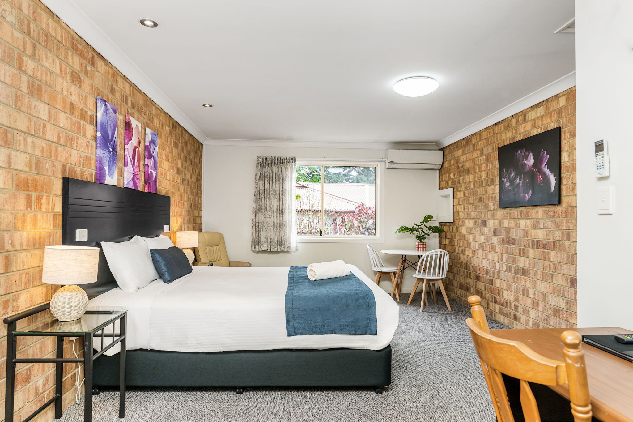 Habitación de hotel con cama, escritorio, silla y ventana con vistas.