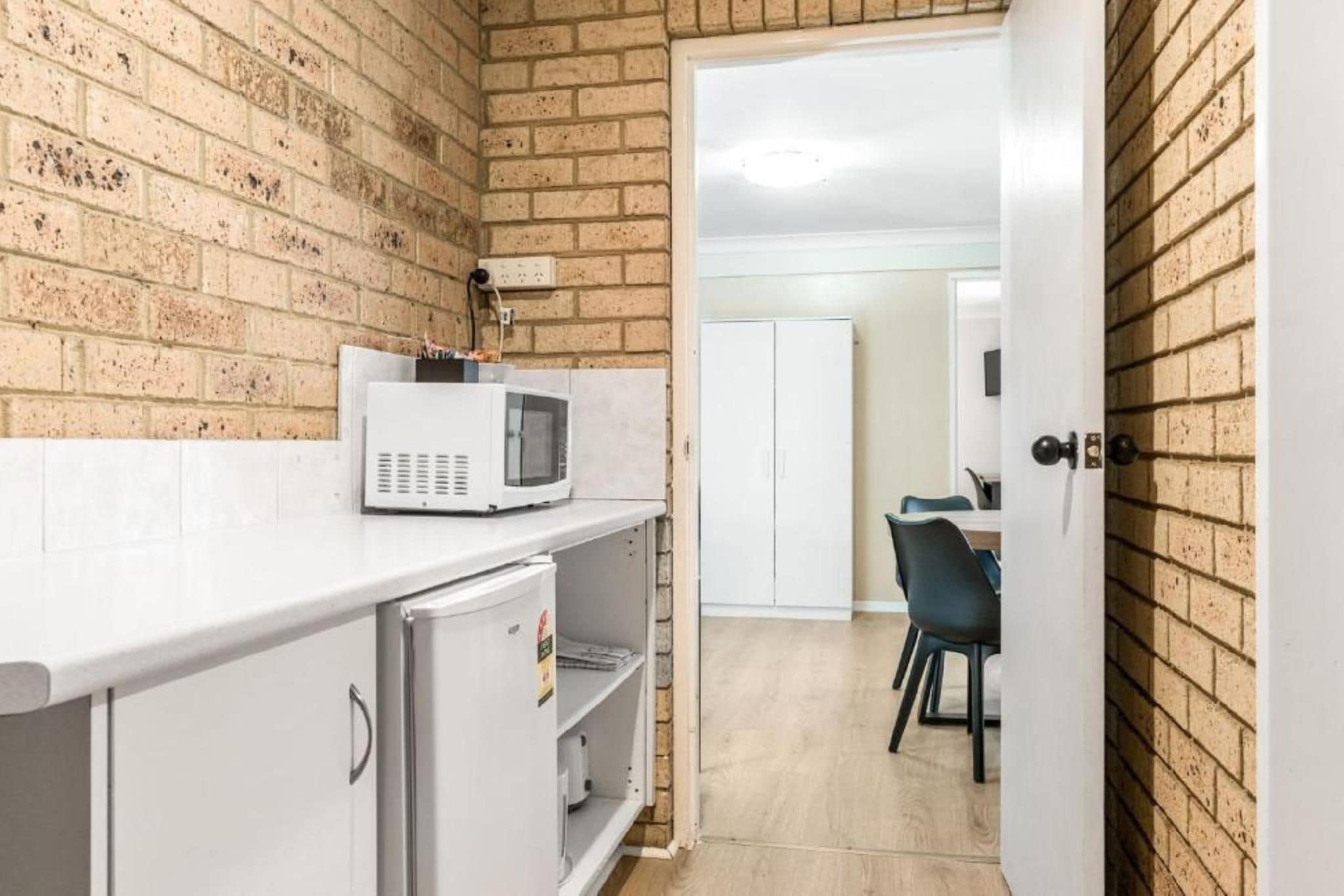 A compact kitchen with a microwave, a small refrigerator, and a dining area with a table and chairs.