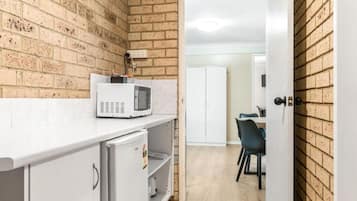A compact kitchen with a microwave, a small refrigerator, and a dining area with a table and chairs.