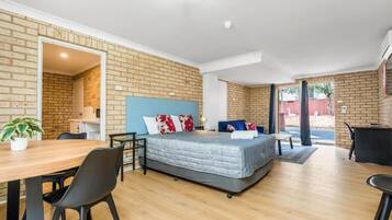 A modern room with a bed, a dining table, and a kitchen area.