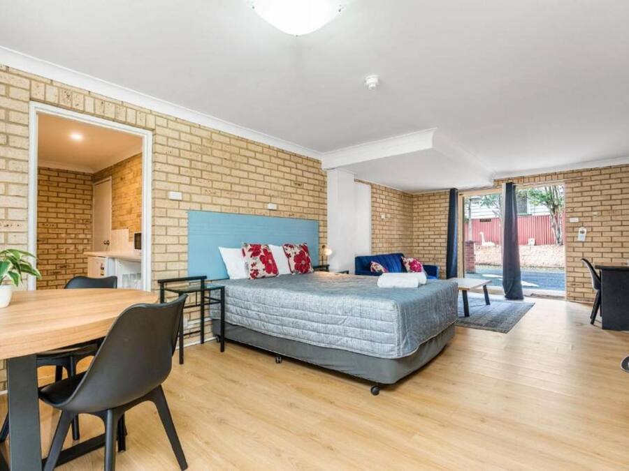 A modern room with a bed, a dining table, and a kitchen area.