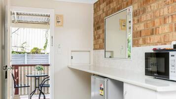 A compact kitchen with a microwave, a small refrigerator, and a white countertop.