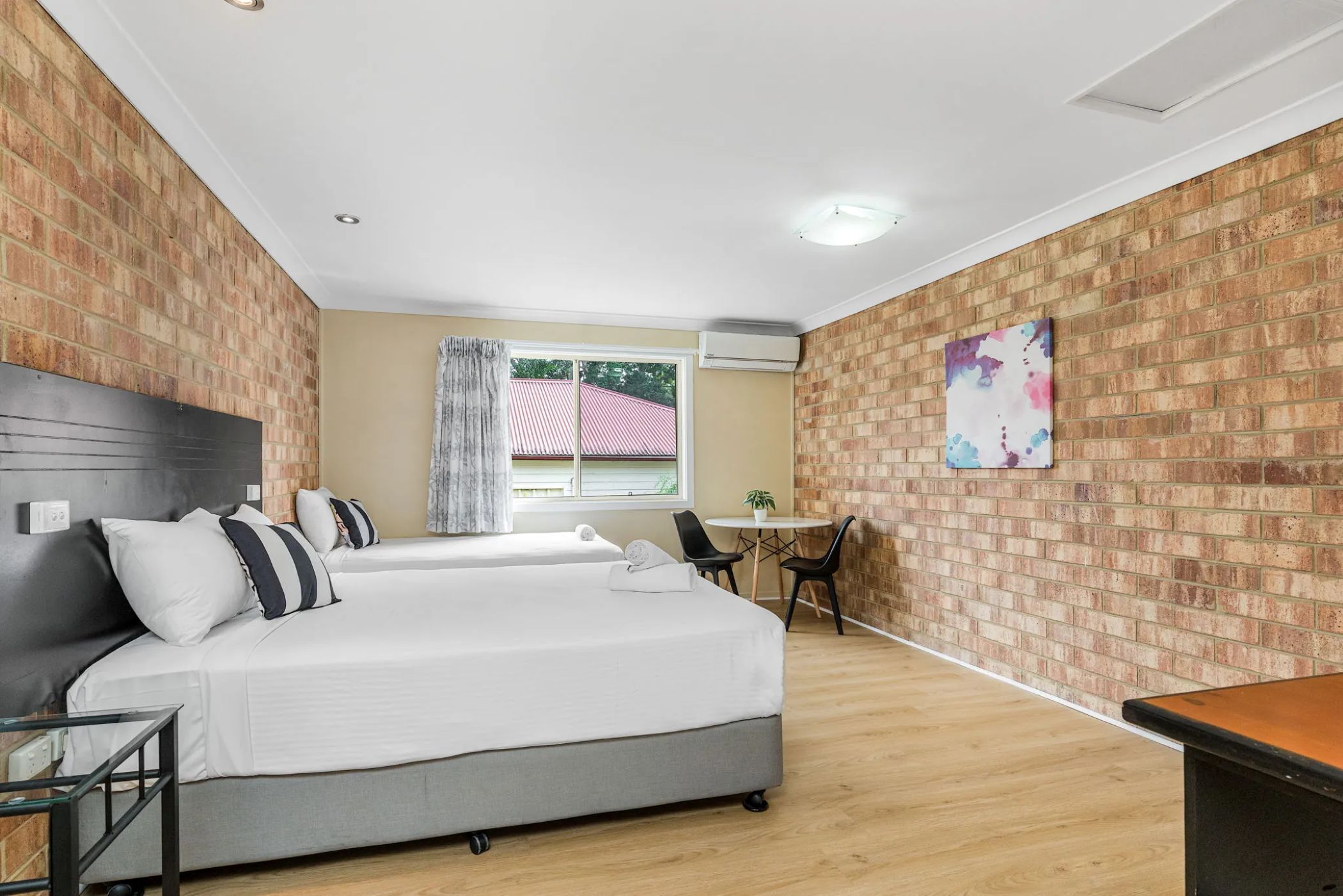 A hotel room with a bed, bedside tables, a desk, and a chair.
