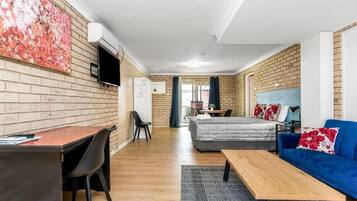 A room with a bed, a sofa, a desk, and a TV mounted on the wall.