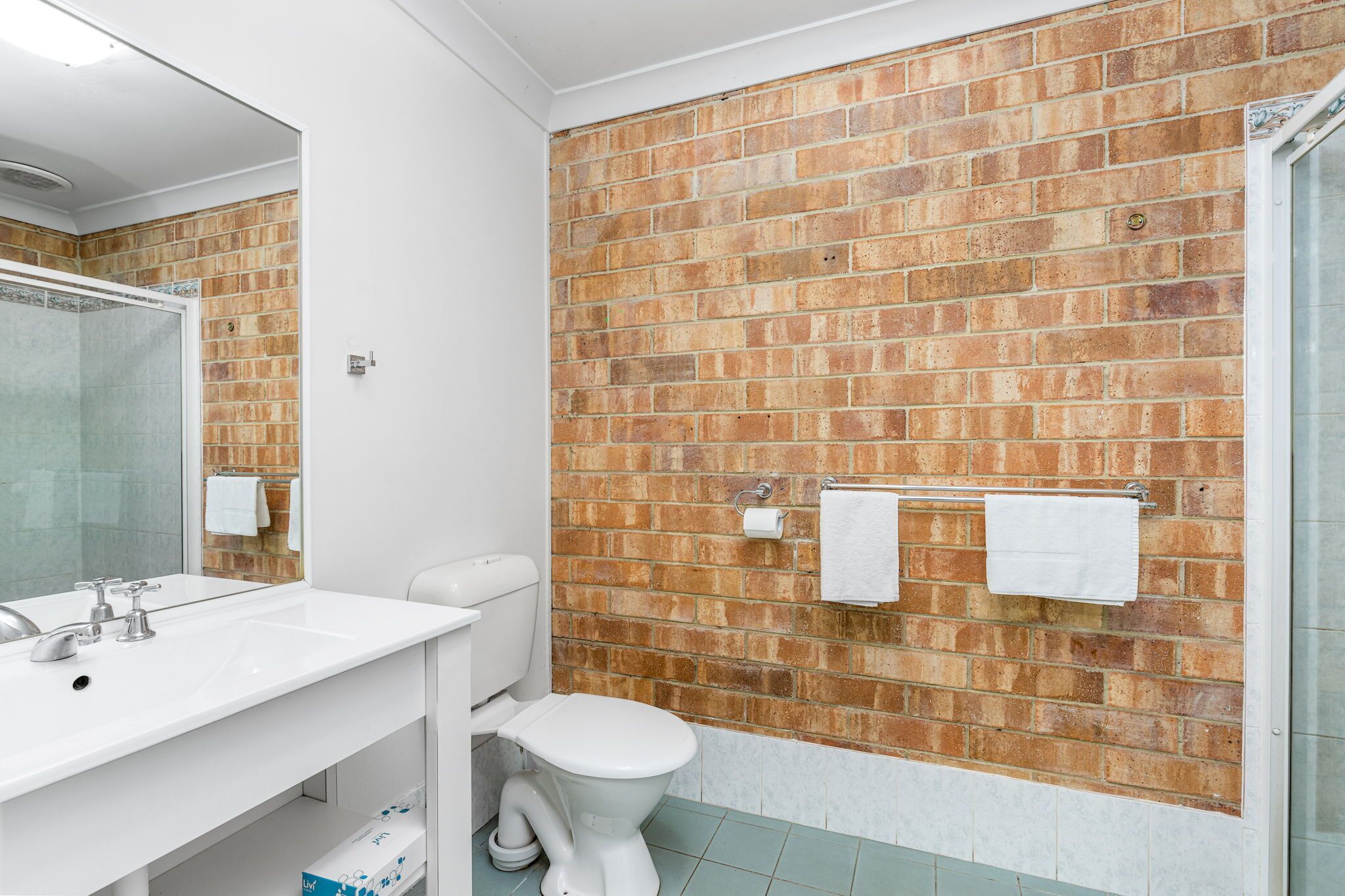 A bathroom with a white sink, a toilet, and a shower area.