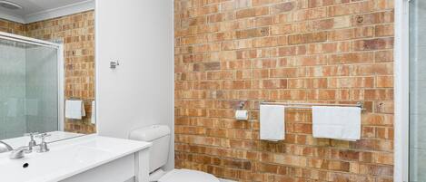 A bathroom with a white sink, a toilet, and a shower area.
