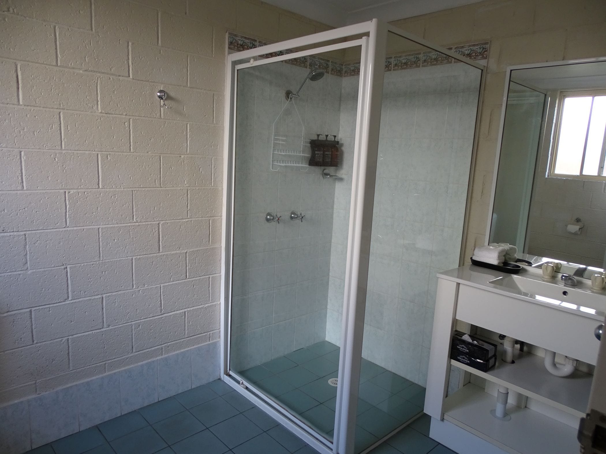 A bathroom with a glass-enclosed shower, a white sink, and a mirror.