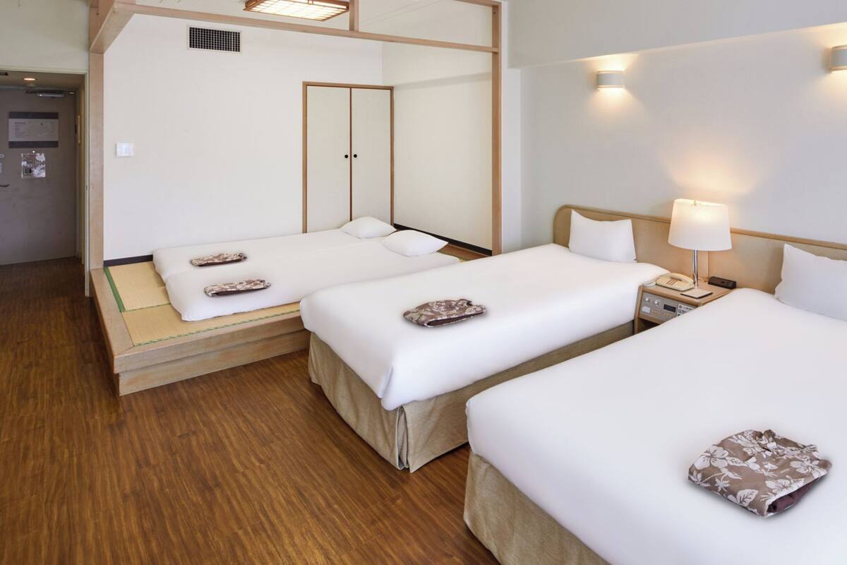 A hotel room with two beds, a mirror, bedside lamps, and a wooden floor.