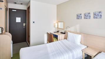 Quarto de hotel com cama, escrivaninha, cadeira, luminária e cafeteira.