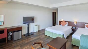 Habitación de hotel con escritorio, dos camas, televisión y una pequeña kitchenette.