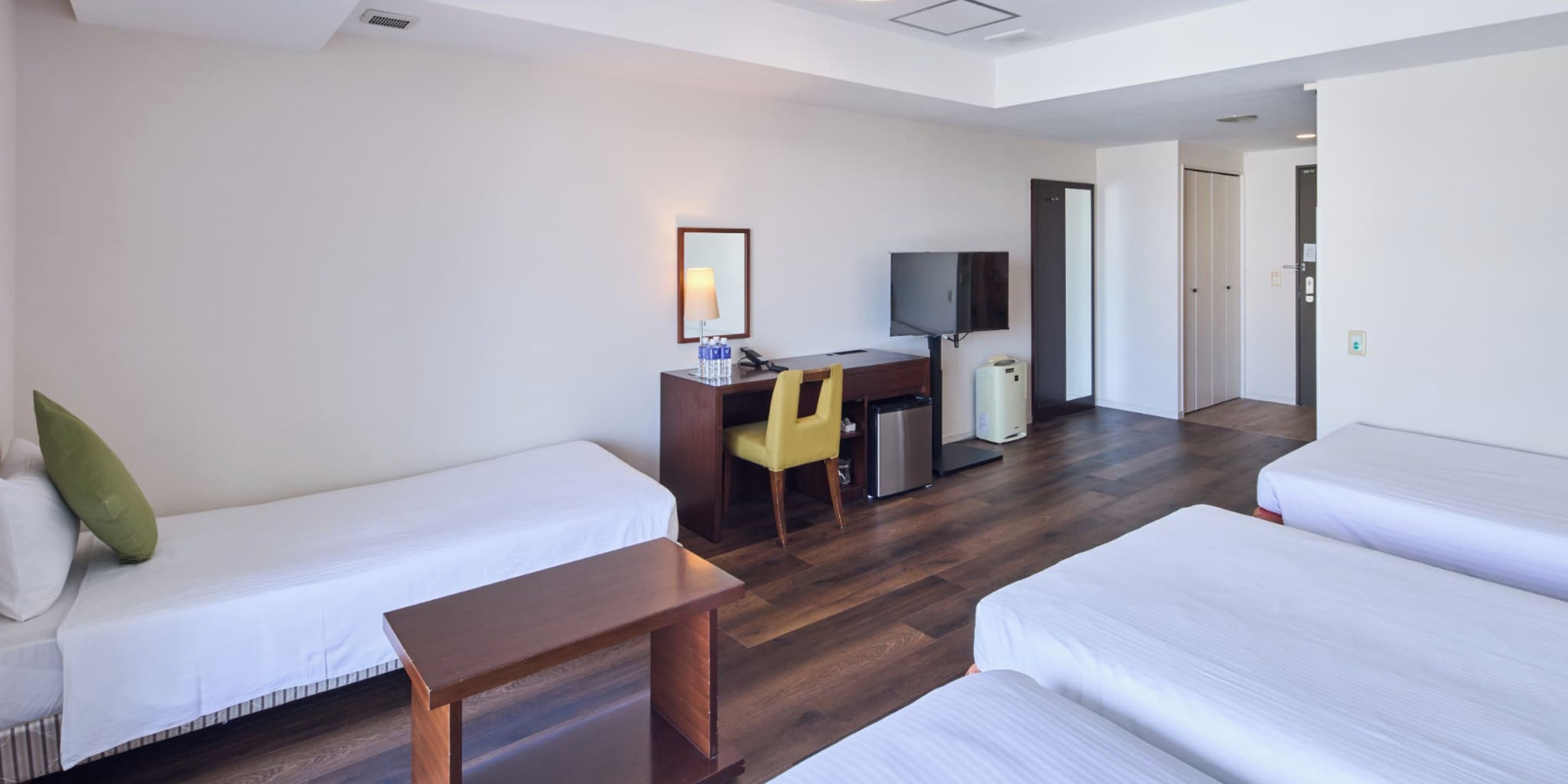 A hotel room with two beds, a desk with a chair, a television, and a waste bin.