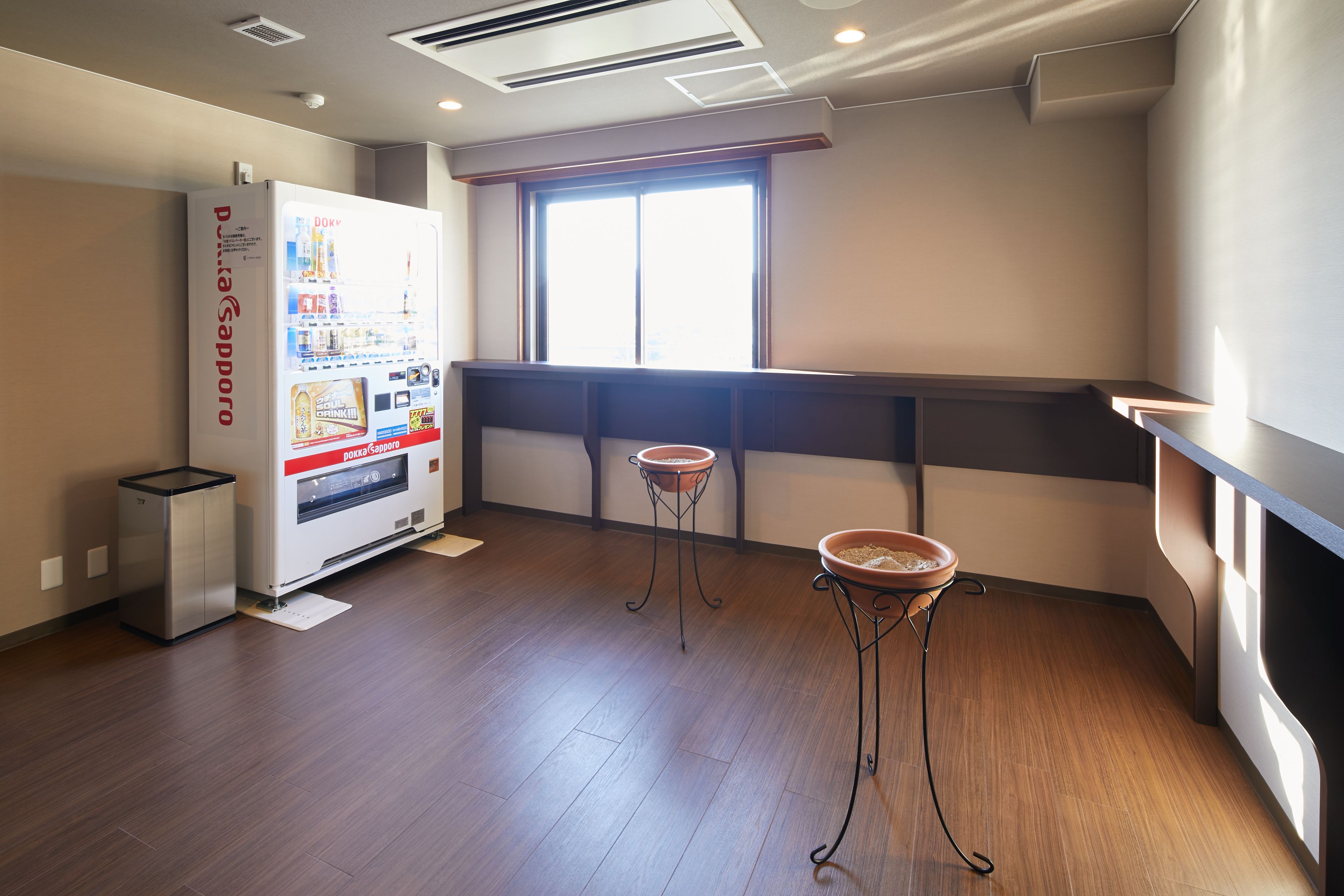 Une pièce équipée d’un distributeur automatique, de deux petites tables avec des bols, d’une fenêtre et d’un plancher en bois.
