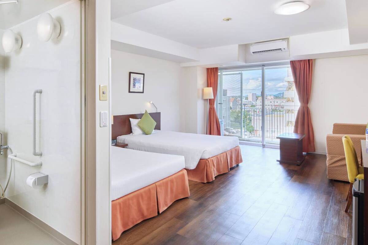 Une chambre d’hôtel avec des toilettes, deux lits, un bureau et un balcon avec vue.