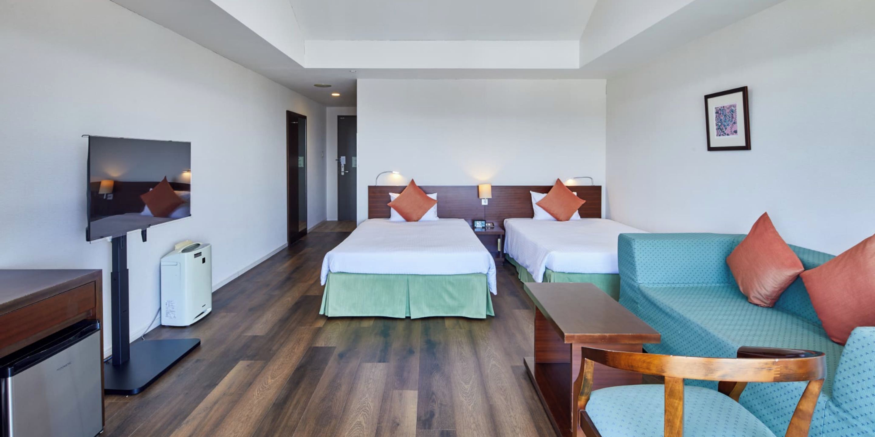 Habitación de hotel con dos camas, un sofá, un televisor y un escritorio con impresora.