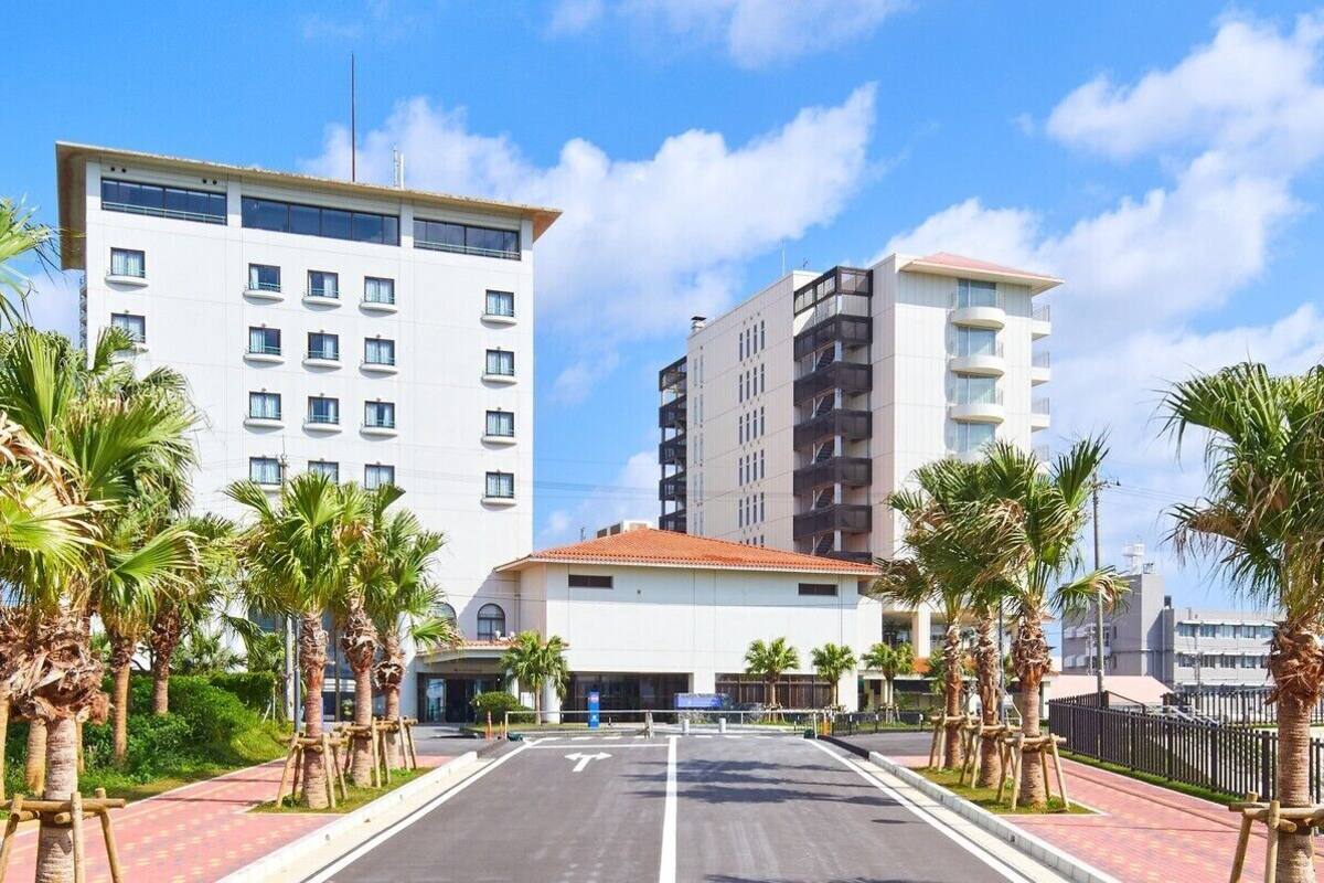 Un hôtel moderne doté d’une cour intérieure, de palmiers et offrant une vue sur un ciel dégagé.
