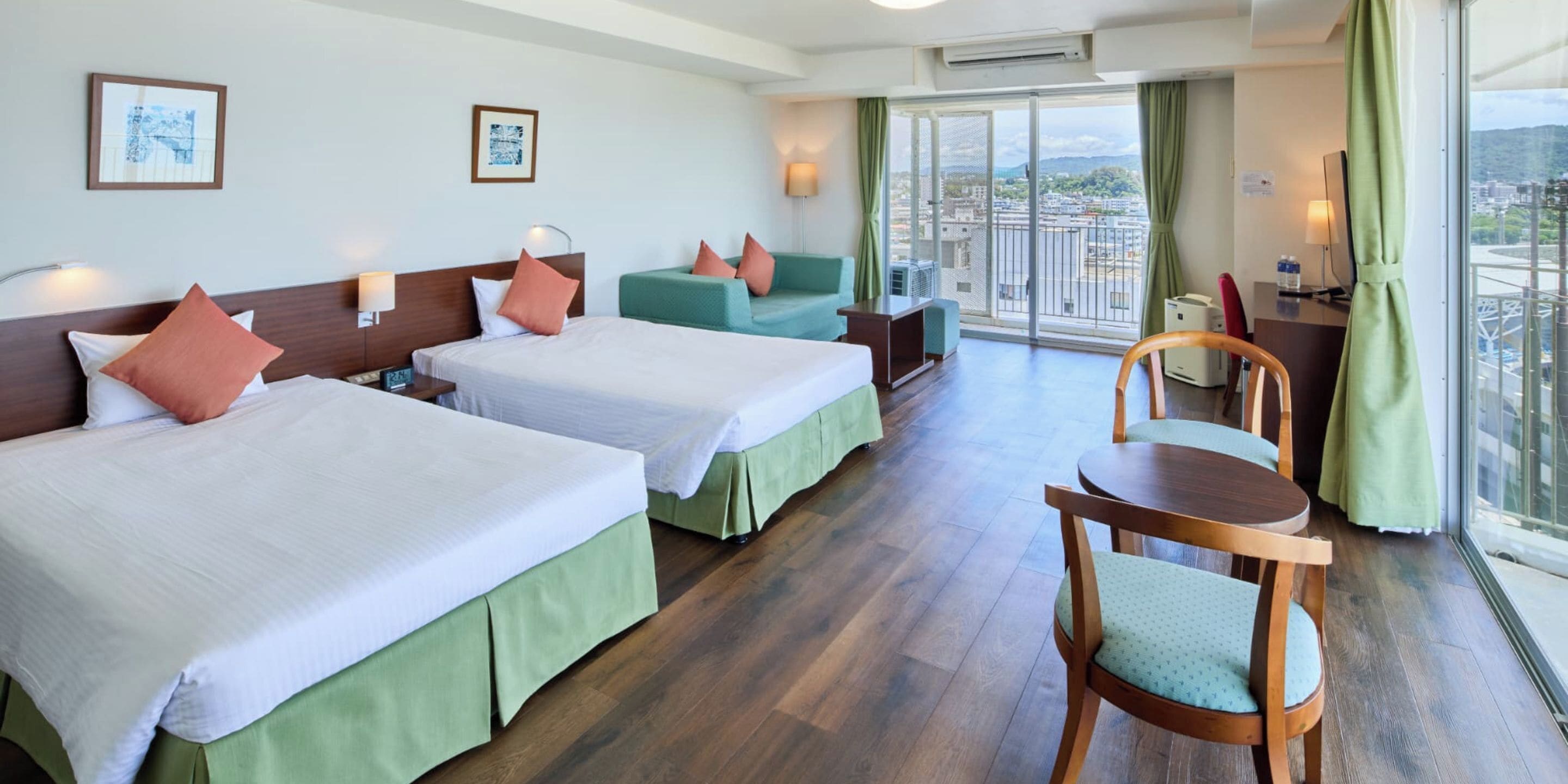 Habitación de hotel con dos camas, un escritorio, una silla y un balcón con vistas.