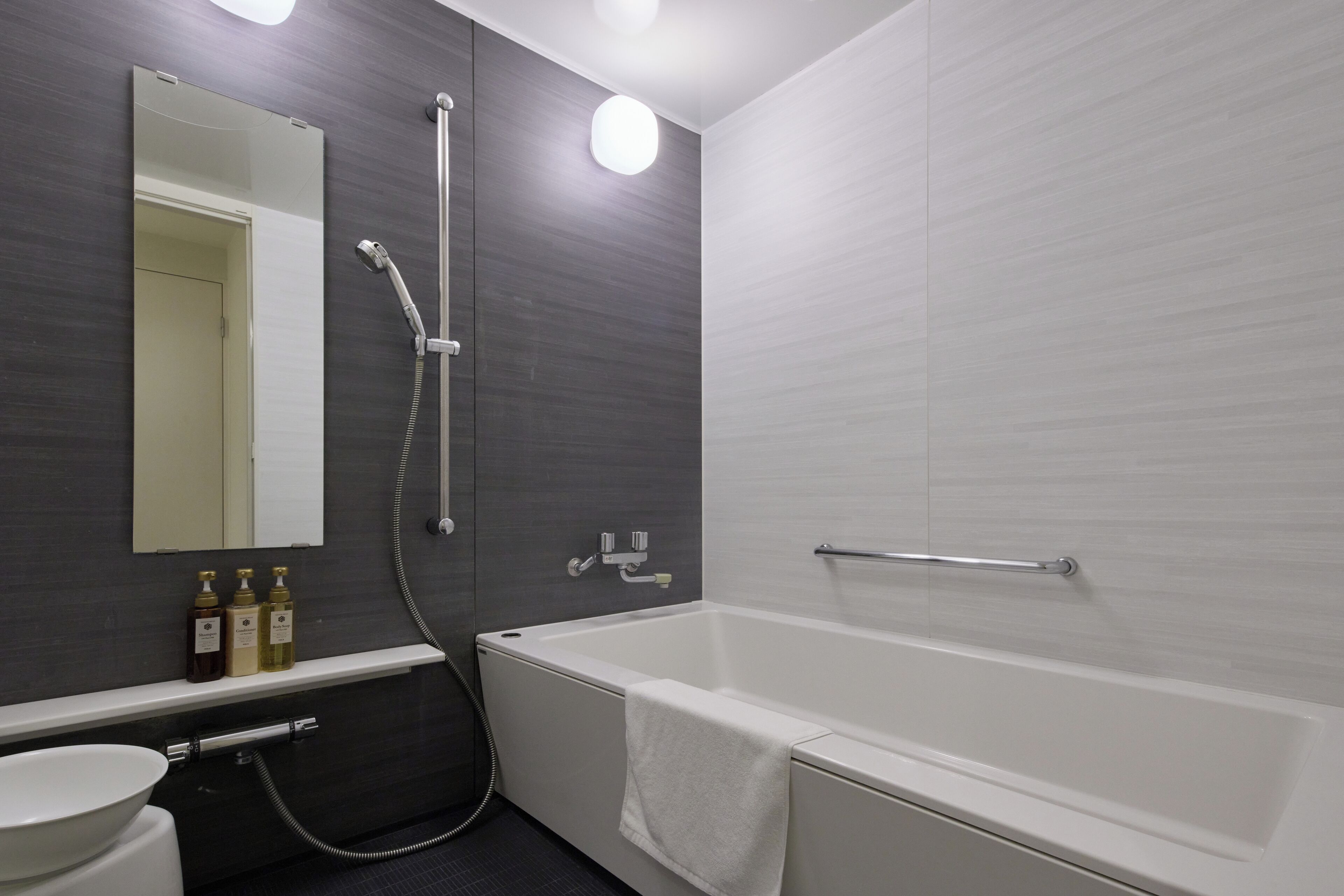 Ein modernes Badezimmer mit Badewanne, Waschbecken, Spiegel und Ablagefläche für Toilettenartikel.