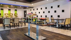 A modern hotel lobby with a central serving area, multiple seating arrangements, and a clean, contemporary design. - TreeHouse Queens Pearl (Gurugram)