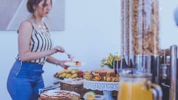 Una mesa de buffet con diversos alimentos y una persona sirviendo.