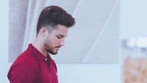 Iemand in een rood polo shirt bedient eten bij een buffet met diverse gerechten en een taart op tafel.