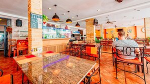 A restaurant with a bar area, wooden tables, and chairs. - High Lords Residence (Pattaya)