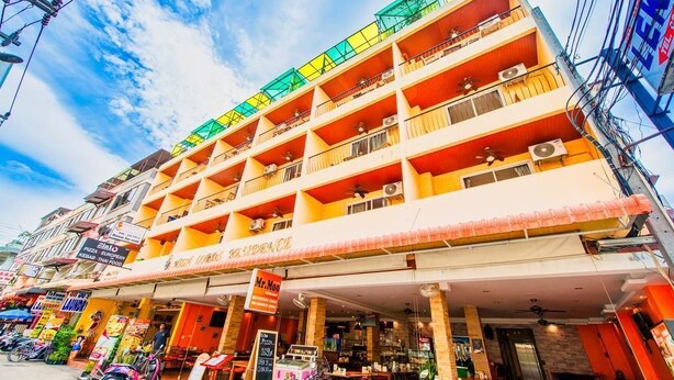 A multi-story building with balconies, a restaurant on the ground floor, and various signs indicating local businesses. - High Lords Residence (Pattaya)