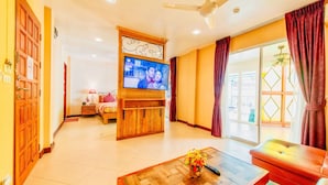 A living room with a television, a wooden coffee table, a sofa, and a sliding glass door leading to an outdoor area. - High Lords Residence (Pattaya)