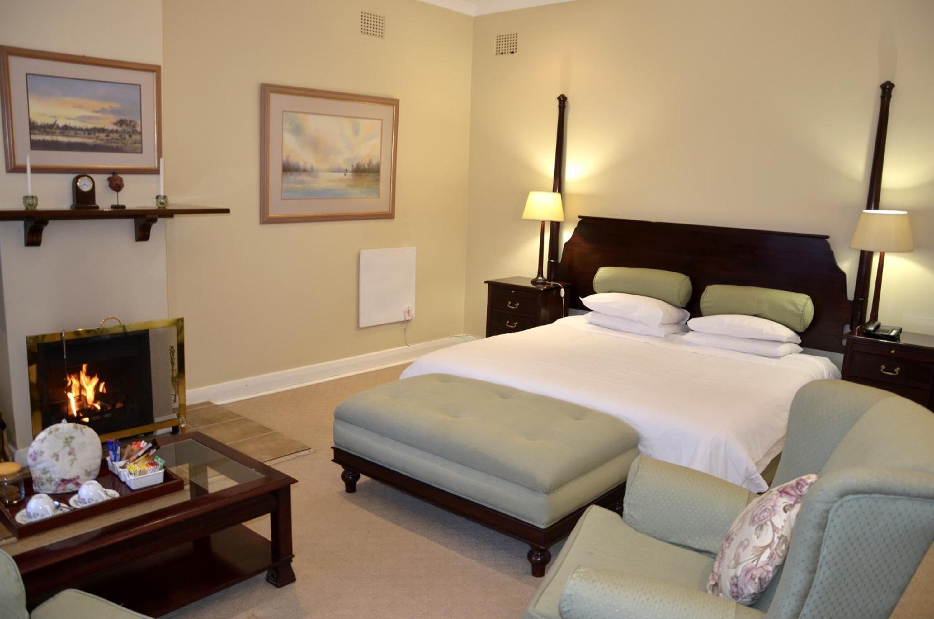 Habitación de hotel con cama, dos mesitas de noche, una mesita auxiliar, una mesa de centro de cristal y una silla.