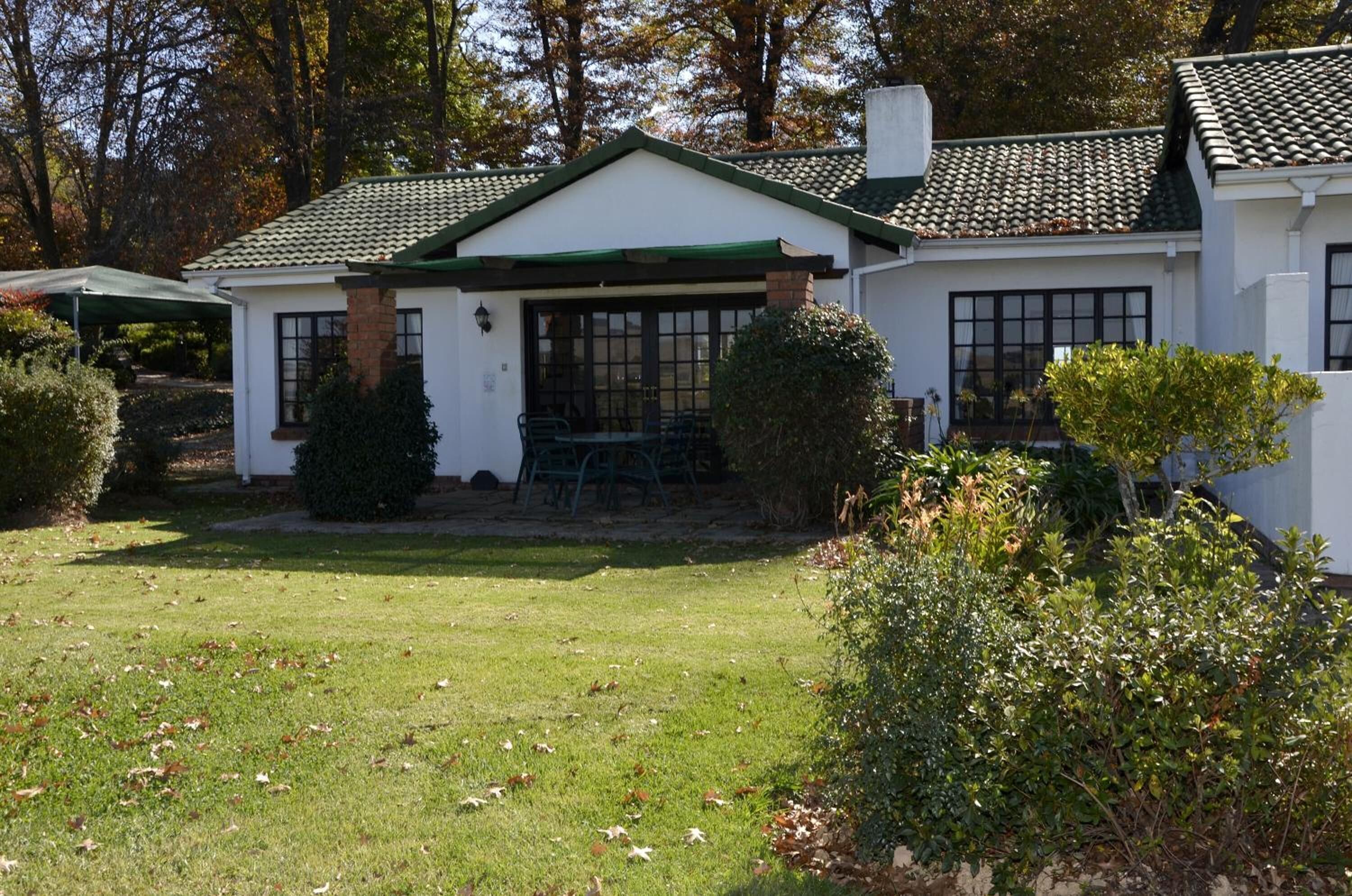 A two-story house with a green roof, a covered patio, and a well-maintained lawn.