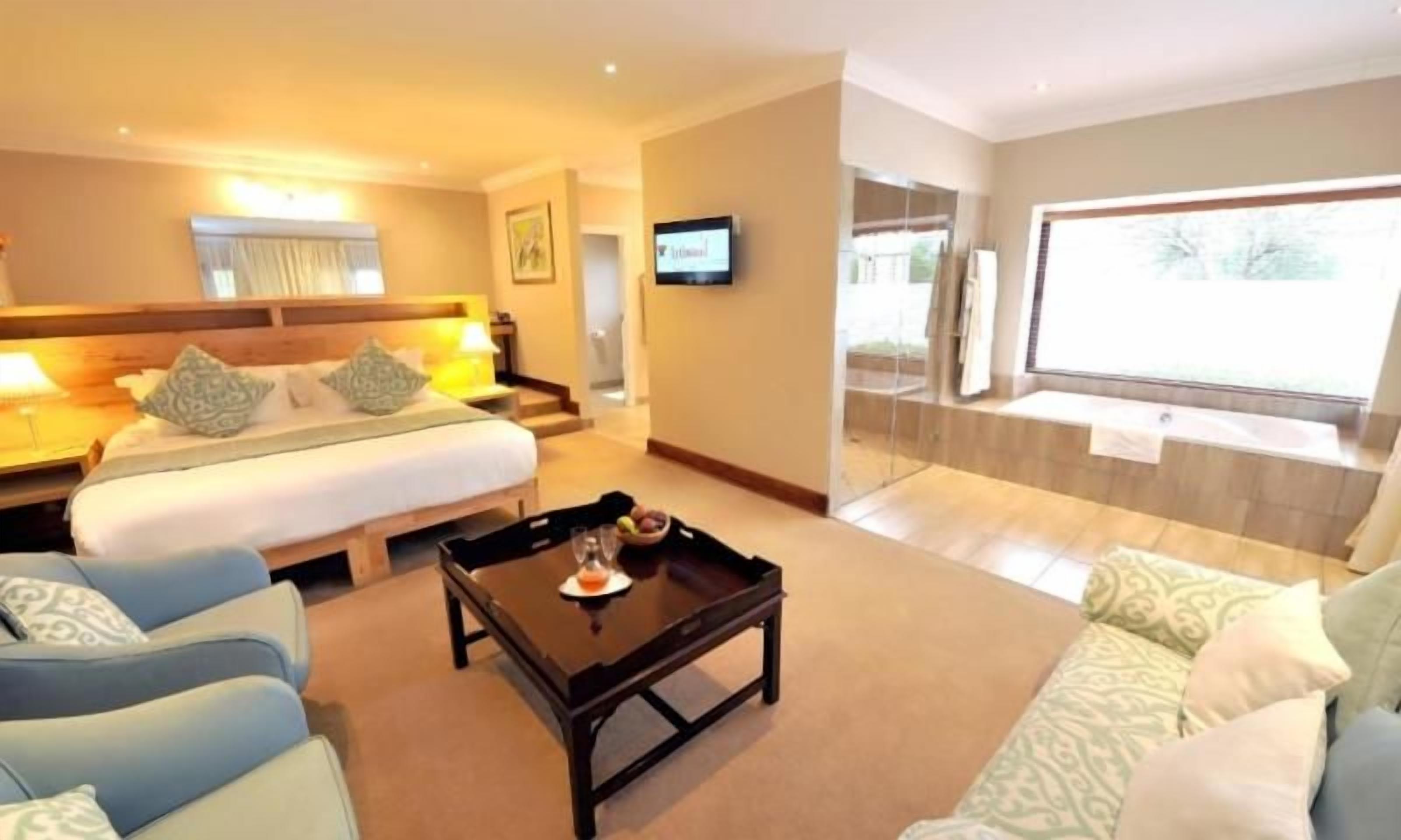 Una habitación de hotel con cama, sofá, mesa de centro y televisor.