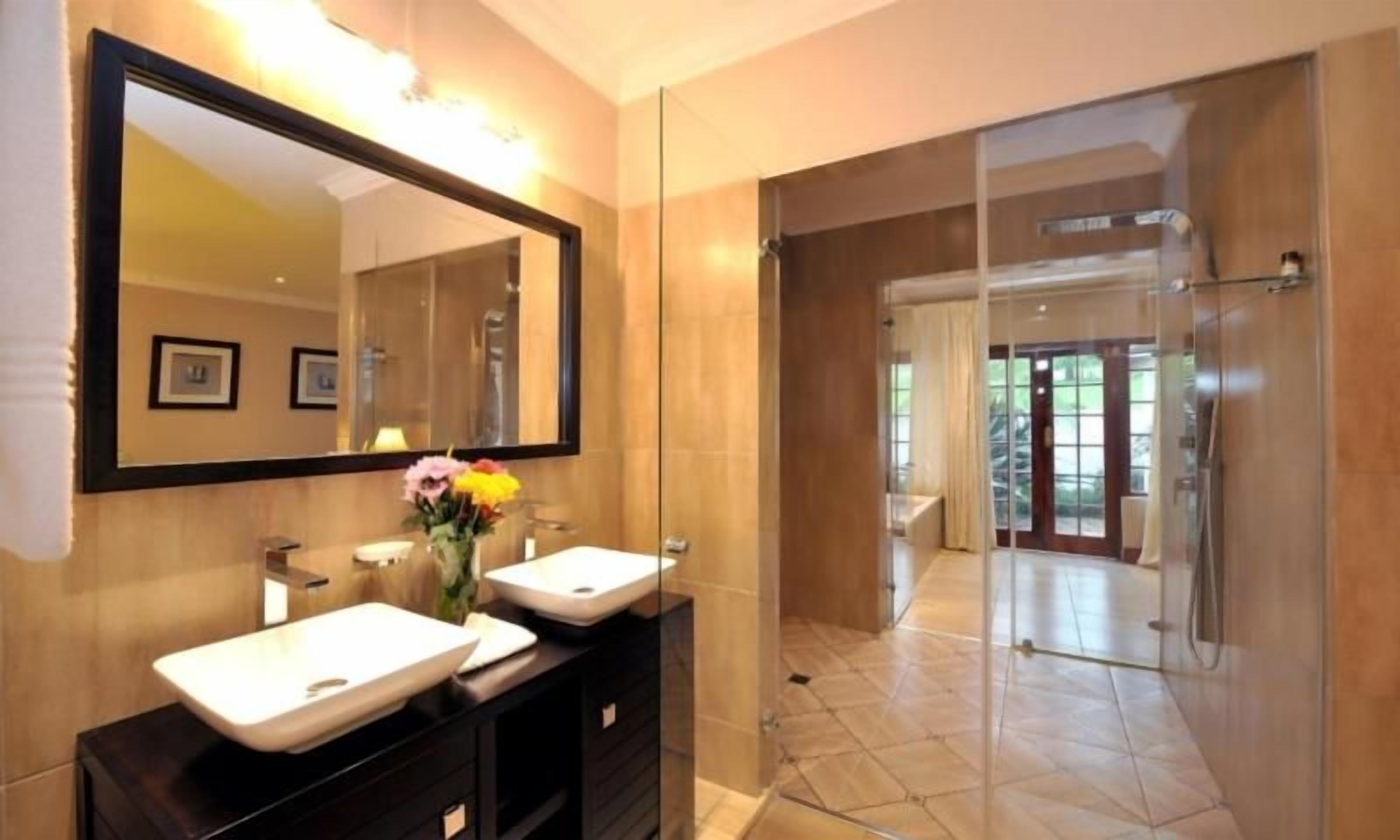 Un baño moderno con dos lavamanos, un espejo grande y un box de ducha de vidrio.