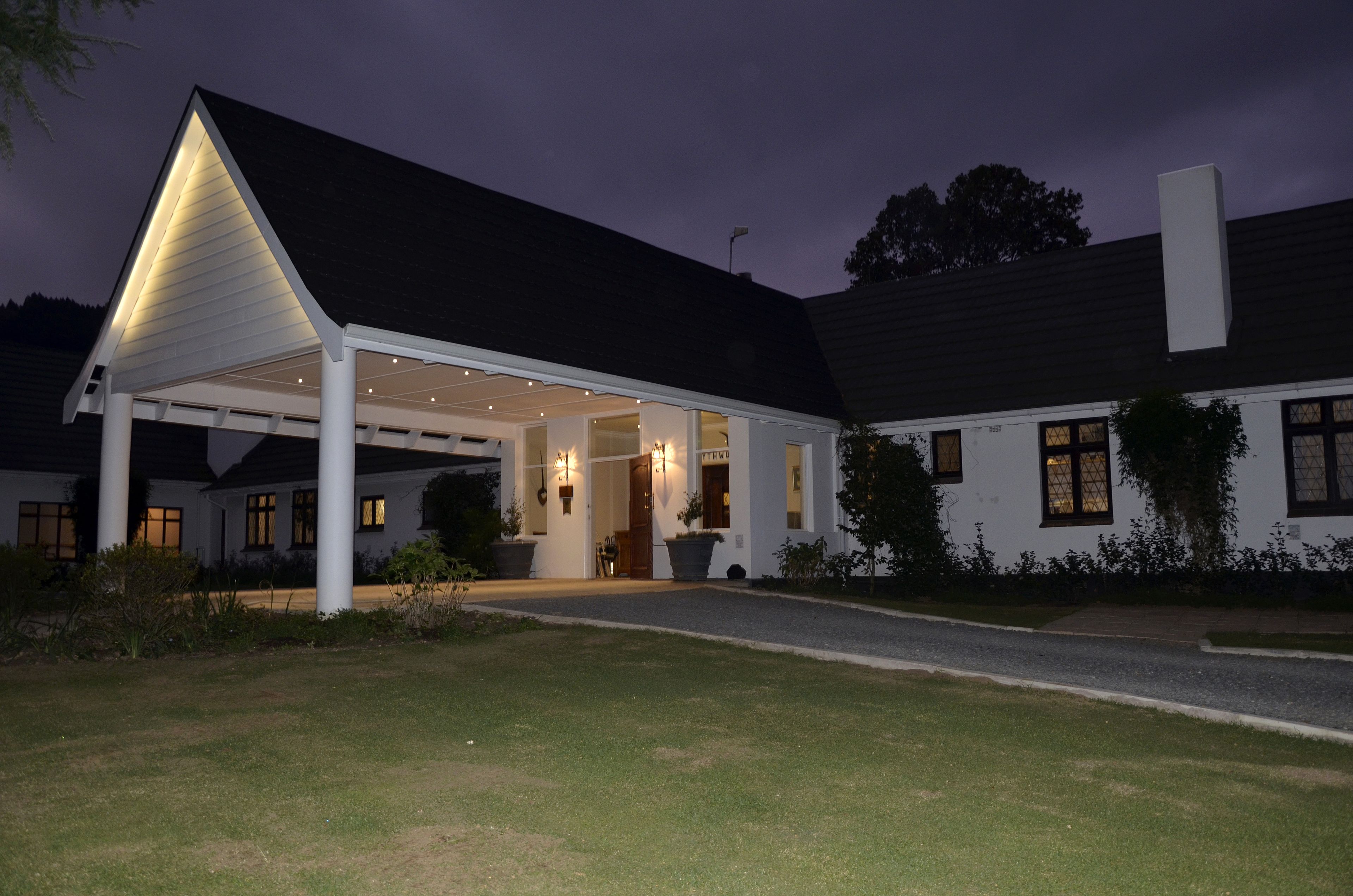 A modern house with a covered patio, large windows, and a well-maintained lawn.