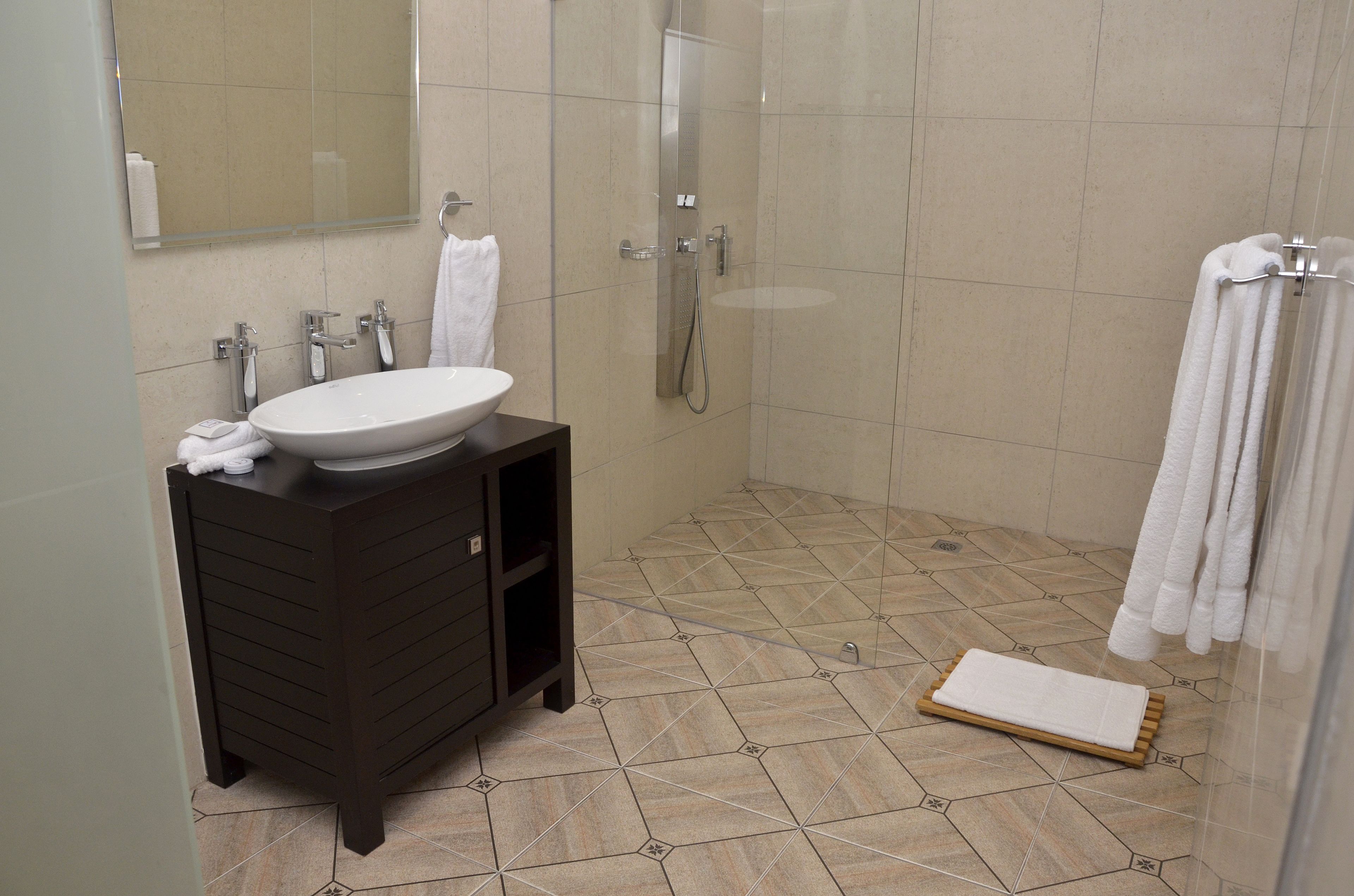 A modern bathroom with a large sink, dark vanity, and a glass shower enclosure.