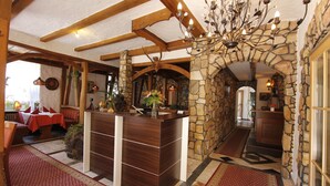 A reception area with a wooden reception desk, stone walls, and a chandelier. - Hotel Rhein-Mosel-View (Urbar)
