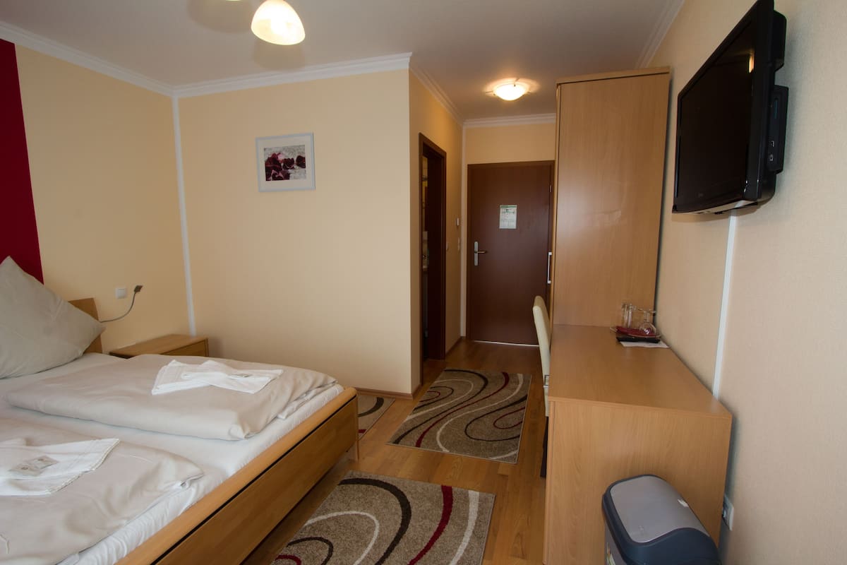 A hotel room with two beds, a desk, a television, and a door leading to another room.