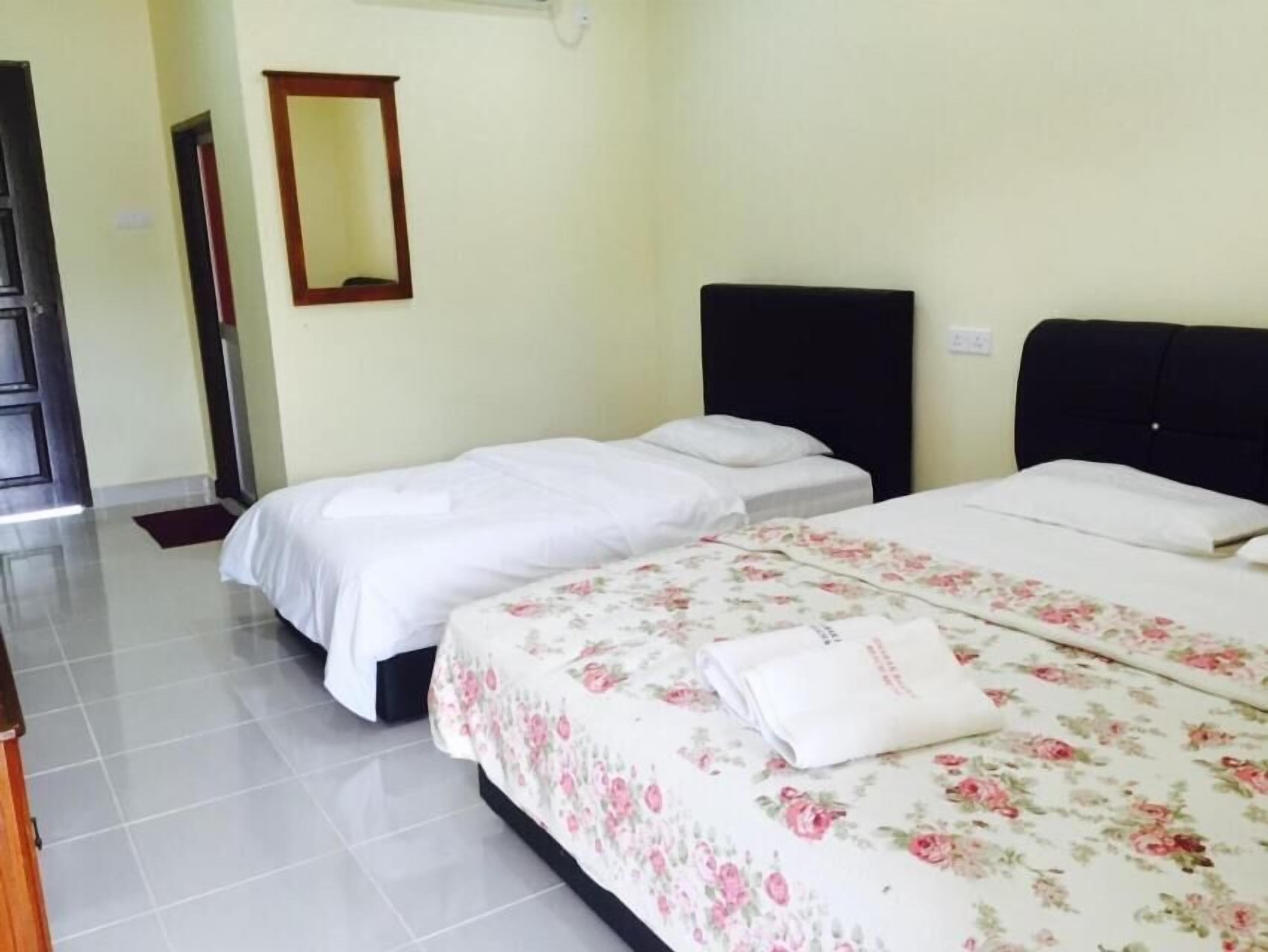 A hotel room with two beds, a mirror, and a tiled floor.