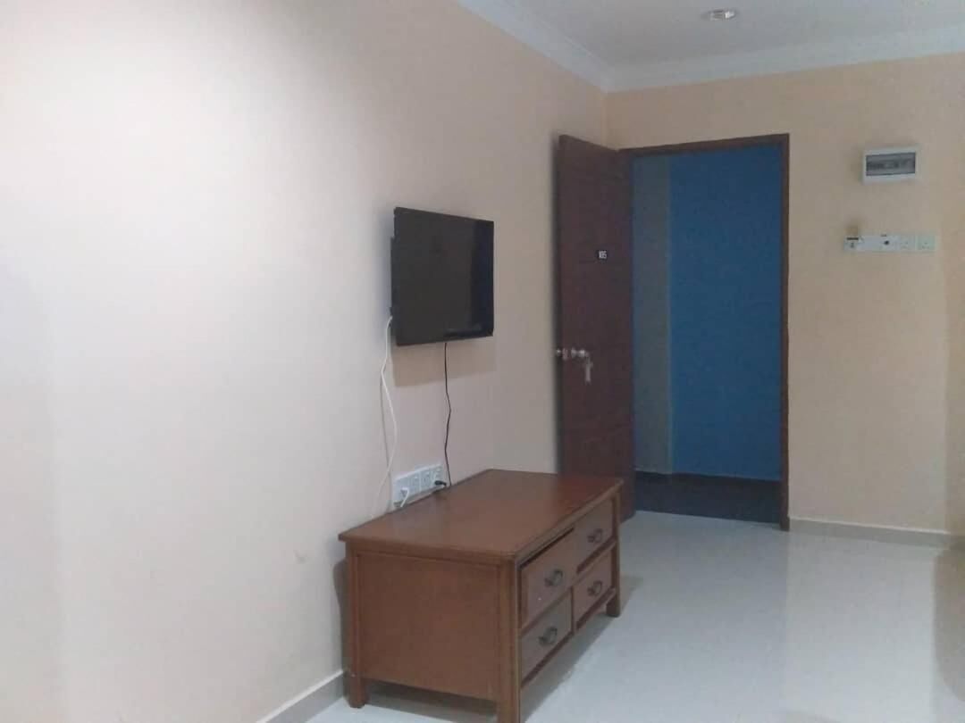 A room with a wooden dresser, a television mounted on the wall, and a blue door.