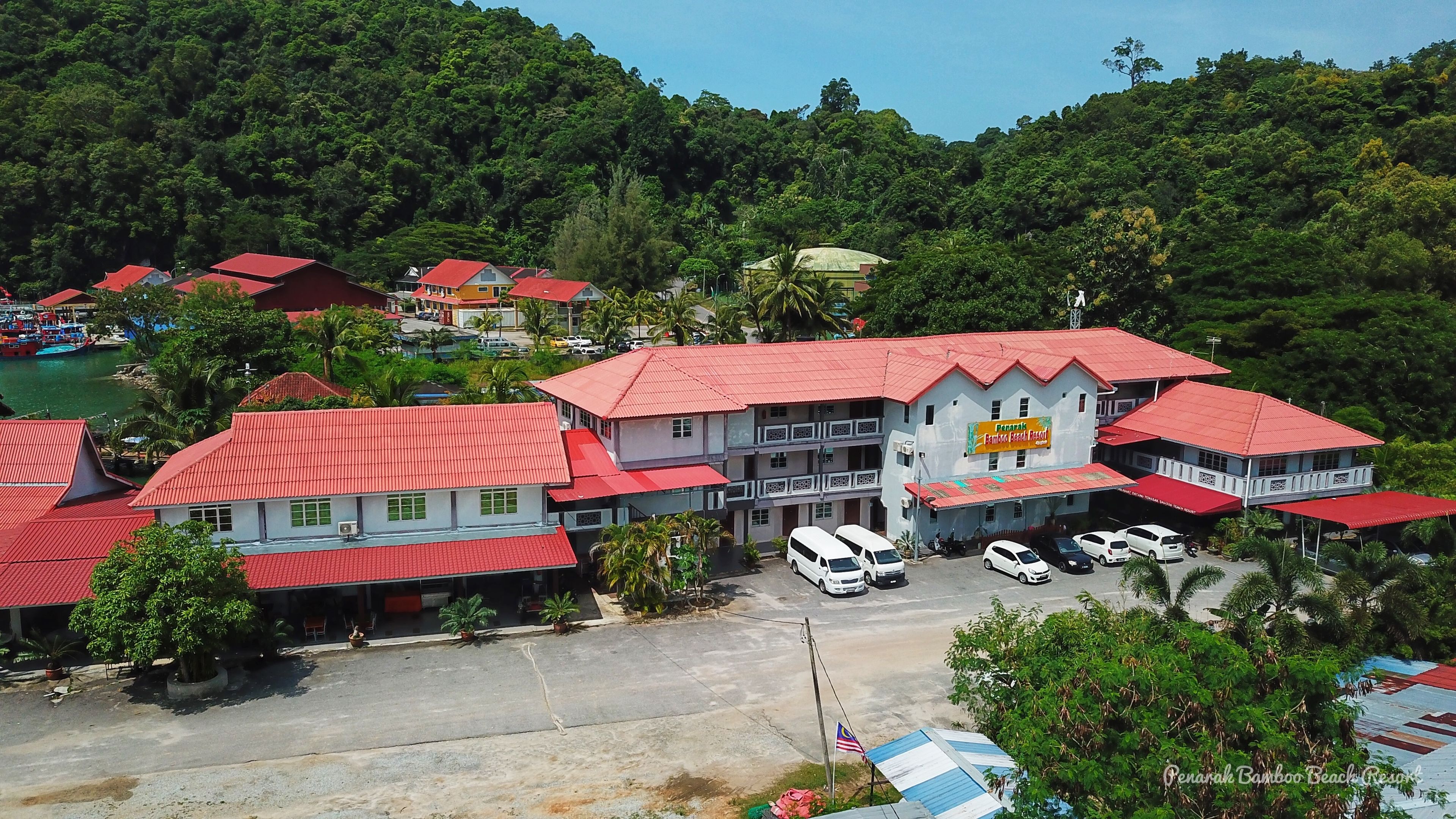 A resort with multiple buildings, red roofs, and a parking area.