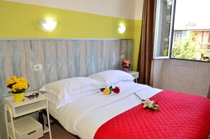 A hotel room with a bed, a nightstand with a flower vase, and a window with curtains. - Hotel New Milan (Milan)
