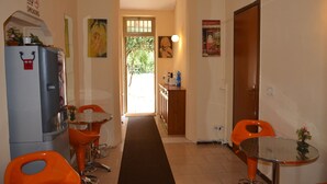 A narrow hallway with a dining area featuring a refrigerator, orange chairs, and a small table. - Hotel New Milan (Milan)
