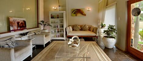 A living room with a sofa, armchairs, a coffee table, and a bookshelf.