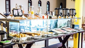 A buffet with various food items, condiments, and beverages. - VELINN Pousada Casa de Pedra Ilhabela (Ilhabela)