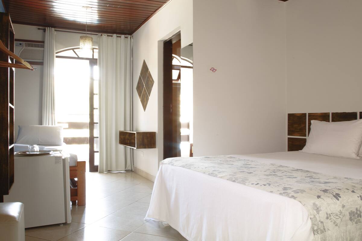 Ein Hotelzimmer mit Bett, Schreibtisch, Stuhl, Lampe und einem Fenster mit Vorhängen.