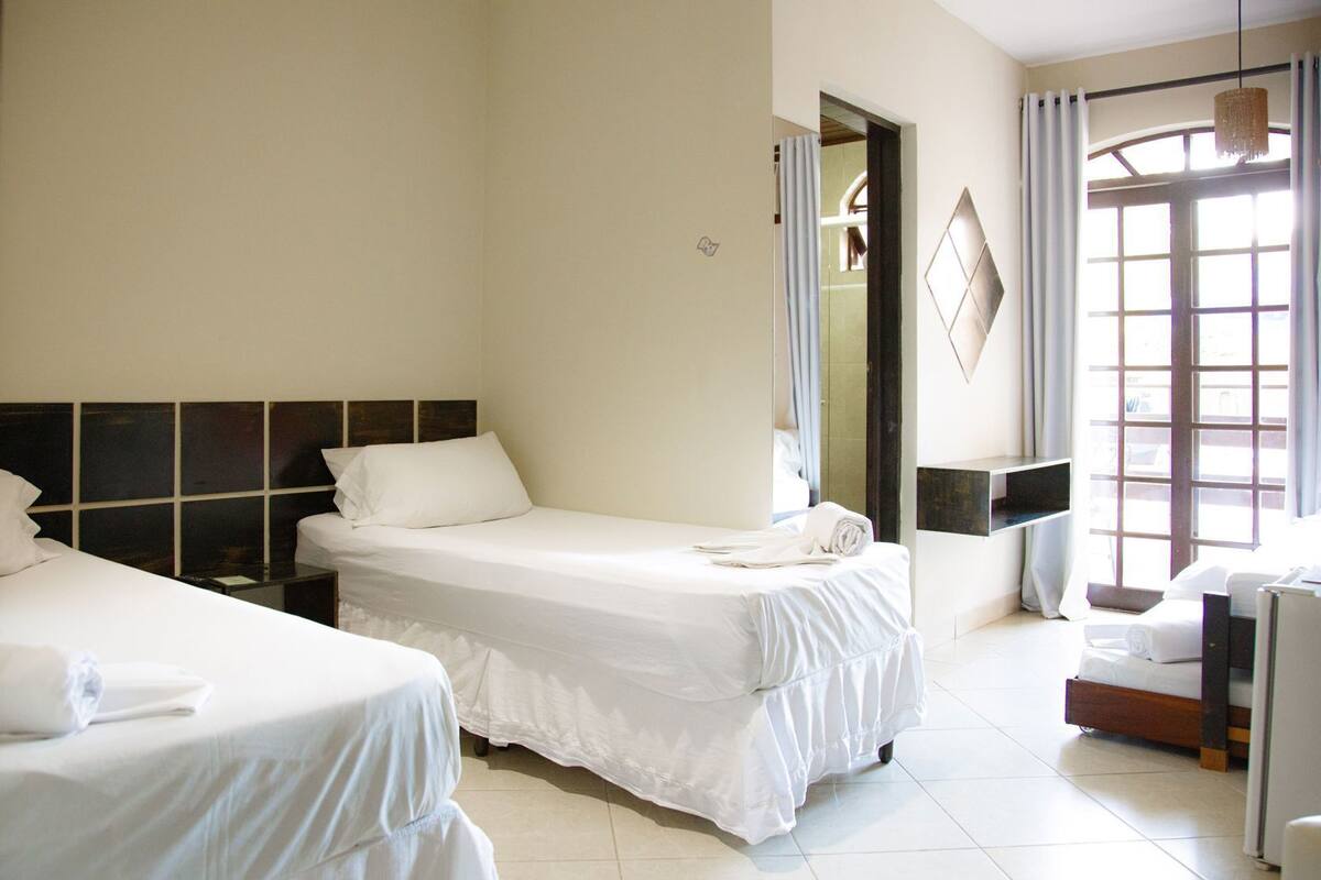 Ein Hotelzimmer mit zwei Betten, einem großen Fenster und einem Spiegel.