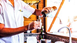 A person pouring a drink into a glass. - VELINN Pousada Casa de Pedra Ilhabela (Ilhabela)