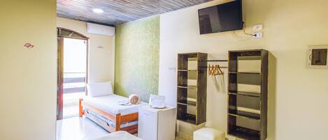 Habitación de hotel con cama, escritorio pequeño, armario y televisor montado en la pared.